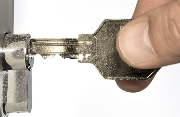 Human fingers inserting key into the door lock