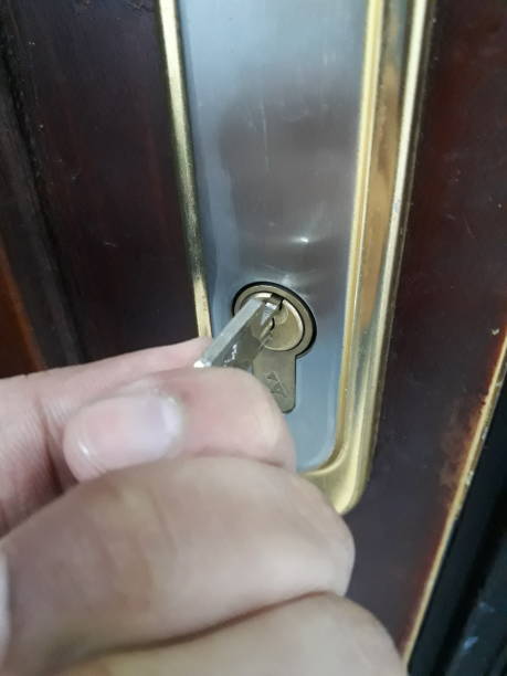 Brown residential door with a hand of a man with a key is about to open the door with newly rekeyed lock by 512 locksmith, best residential rekey services in Austin Tx